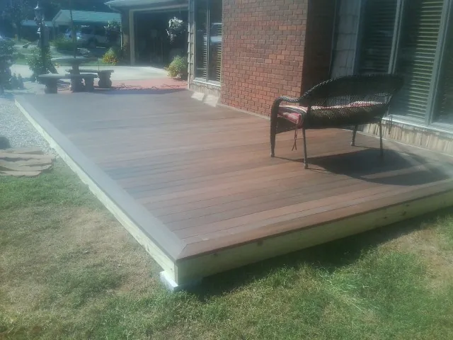 New wood deck and wicker chair beside a brick house in Martin